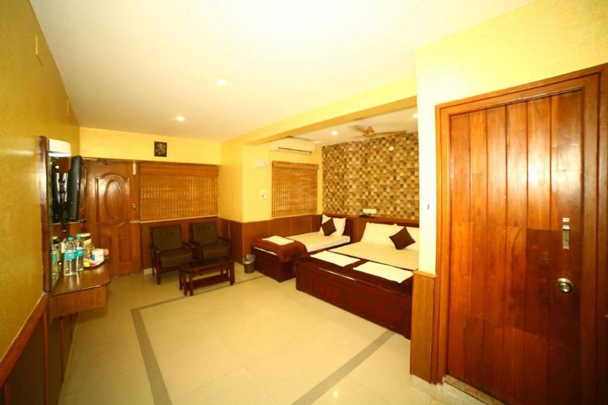 A hotel room with a large bed, a desk with a chair, a small sofa, and a wooden wardrobe.