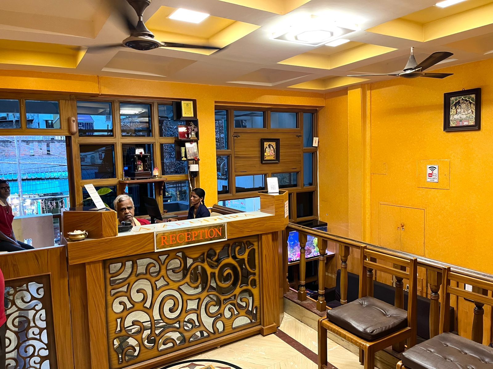 A reception area with a wooden reception desk, a ceiling fan, and a view of the street outside.