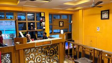 A reception area with a wooden reception desk, a ceiling fan, and a view of the street outside.