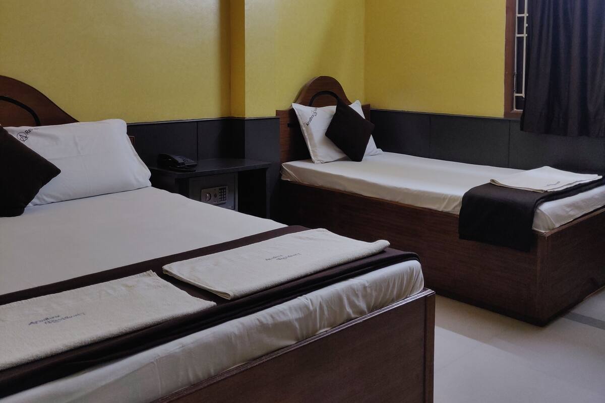 A hotel room with two single beds, a small desk with a telephone, and a window with curtains.