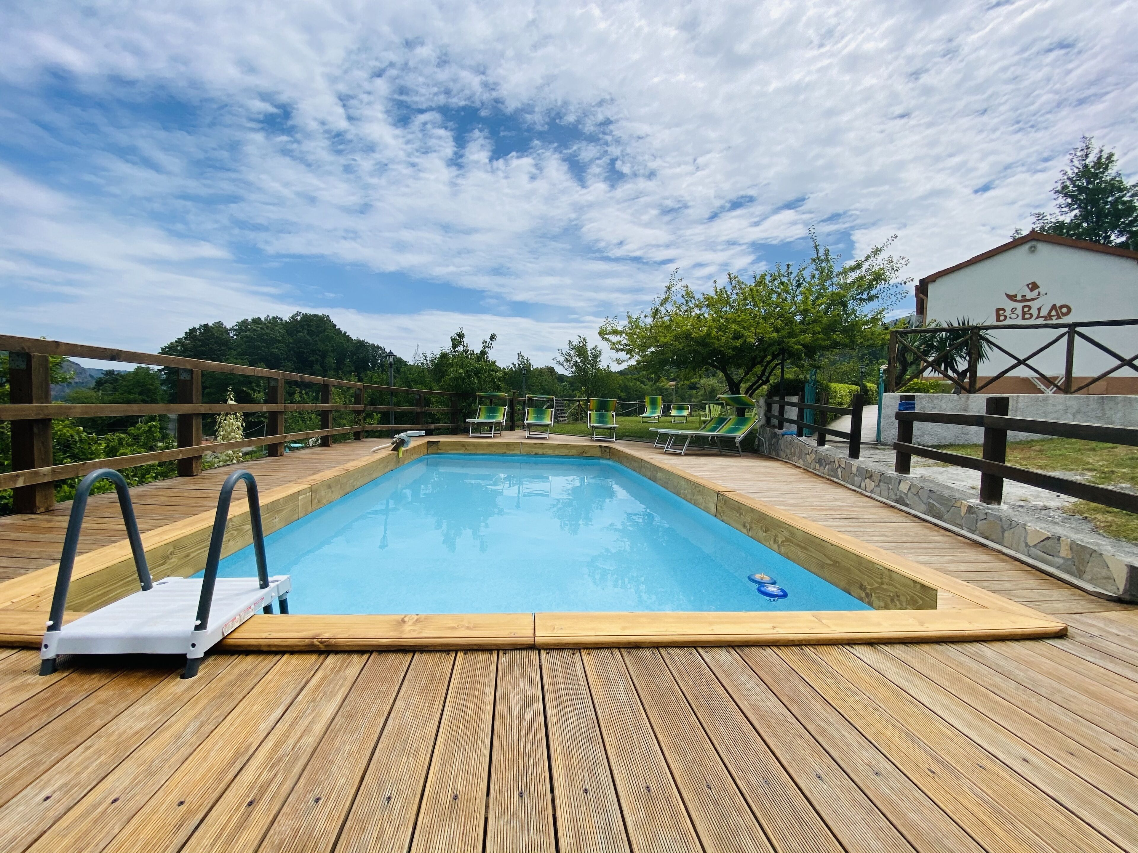 Una terraza de madera con piscina, sillas de descanso y un letrero con el nombre 'B&B BIAO'.
