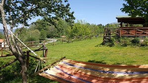 A hammock tied to a tree in a grassy area with a wooden structure in the background. - B&B Lao (Papasidero)