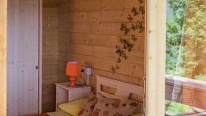 A bedroom with a wooden headboard, a nightstand with a lamp, and a window with a view of trees. - B&B Lao (Papasidero)