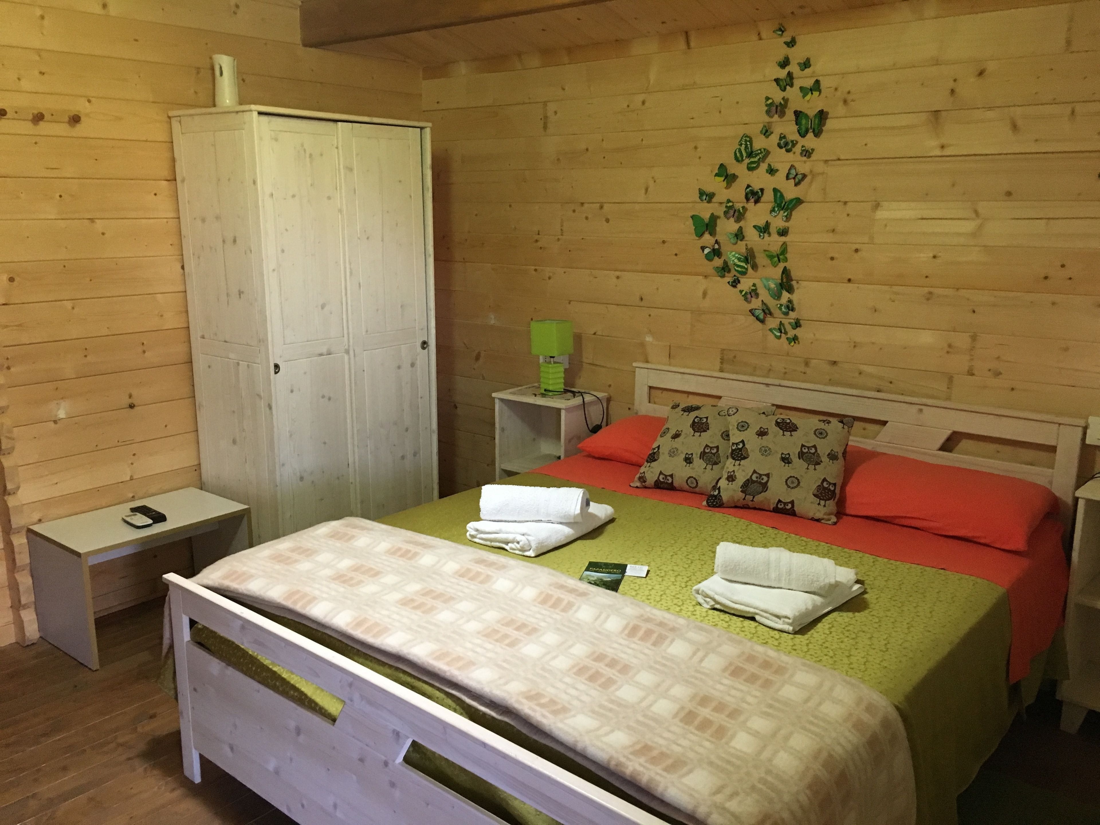 A wooden room with a bed, a wardrobe, and a nightstand.