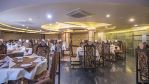 A spacious dining area with round tables and chairs, a high ceiling with recessed lighting, and a modern design. - Hotel Nisarga (Bhopal)