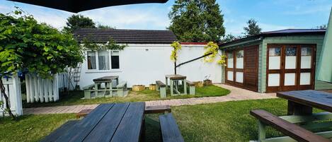 A backyard with a picnic table, a small shed, and a white house with a green roof.