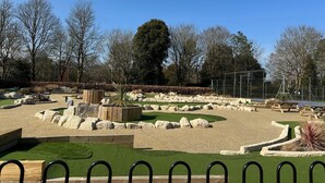 A landscaped park with a variety of rock formations, a wooden bench, and a fenced area with picnic tables. - Oxford Guest House (Oxford)