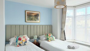 A hotel room with two beds, a large window with curtains, a ceiling light, and a framed picture on the wall. - Oxford Guest House (Oxford)