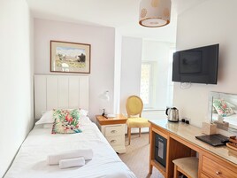 Habitación de hotel con cama, escritorio, silla, televisor y ventana con vista a un edificio.