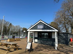 A small building with a sign reading "Courtside at Bury Knowle" and a picnic table in front.