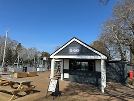 A small building with a sign reading "Courtside at Bury Knowle" and a picnic table in front.