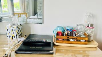 Una habitación de hotel con una computadora portátil, una caja de pañuelos, un espejo y una bandeja con bocadillos y una botella de agua.