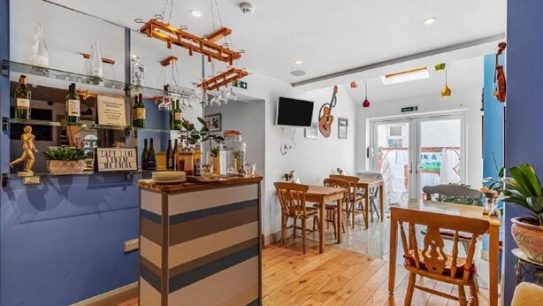 A restaurant with a bar area, wooden chairs, and a counter with bottles. - Oxford Guest House (Oxford)