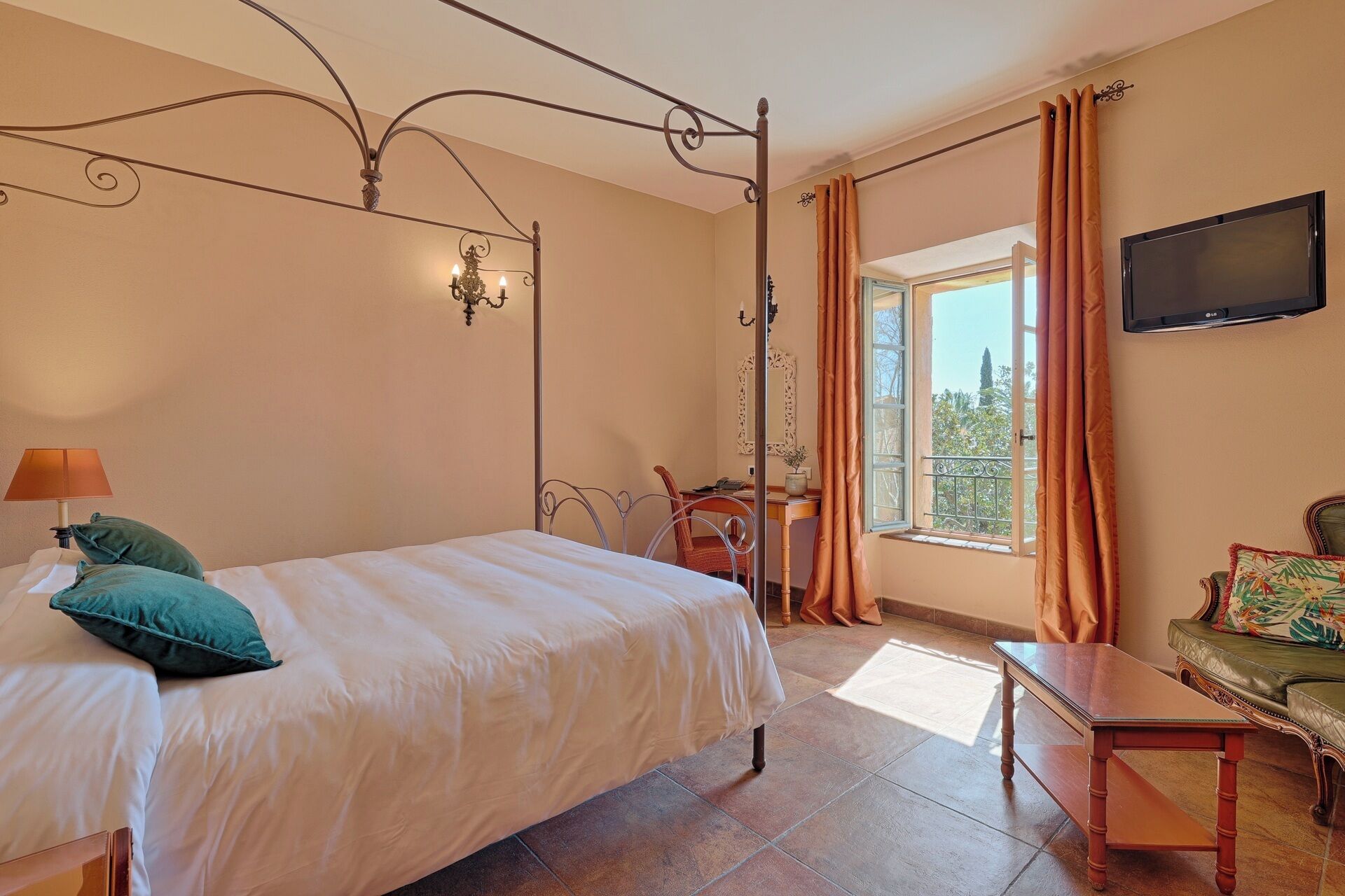 Une chambre à coucher avec un lit, un bureau, une chaise, un téléviseur et une fenêtre avec des rideaux.