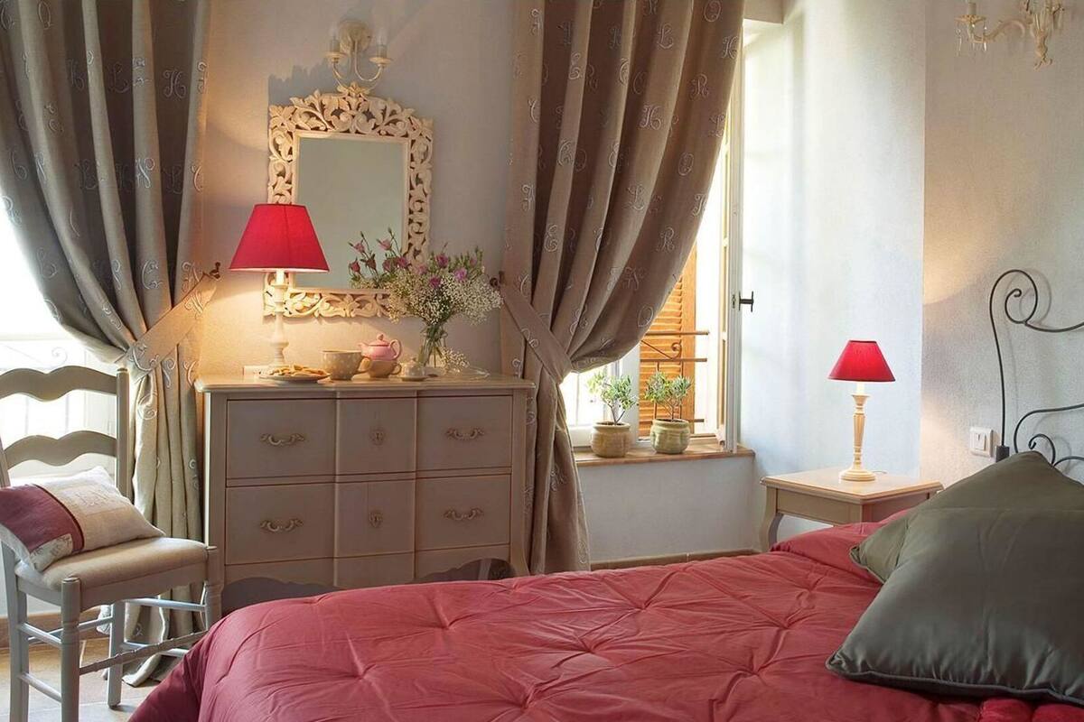 Un dormitorio con una cama, un aparador, una silla, un espejo y dos lámparas.