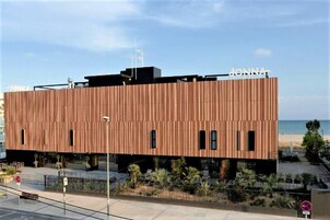 Un edificio moderno con fachada de madera, cerca de una playa.