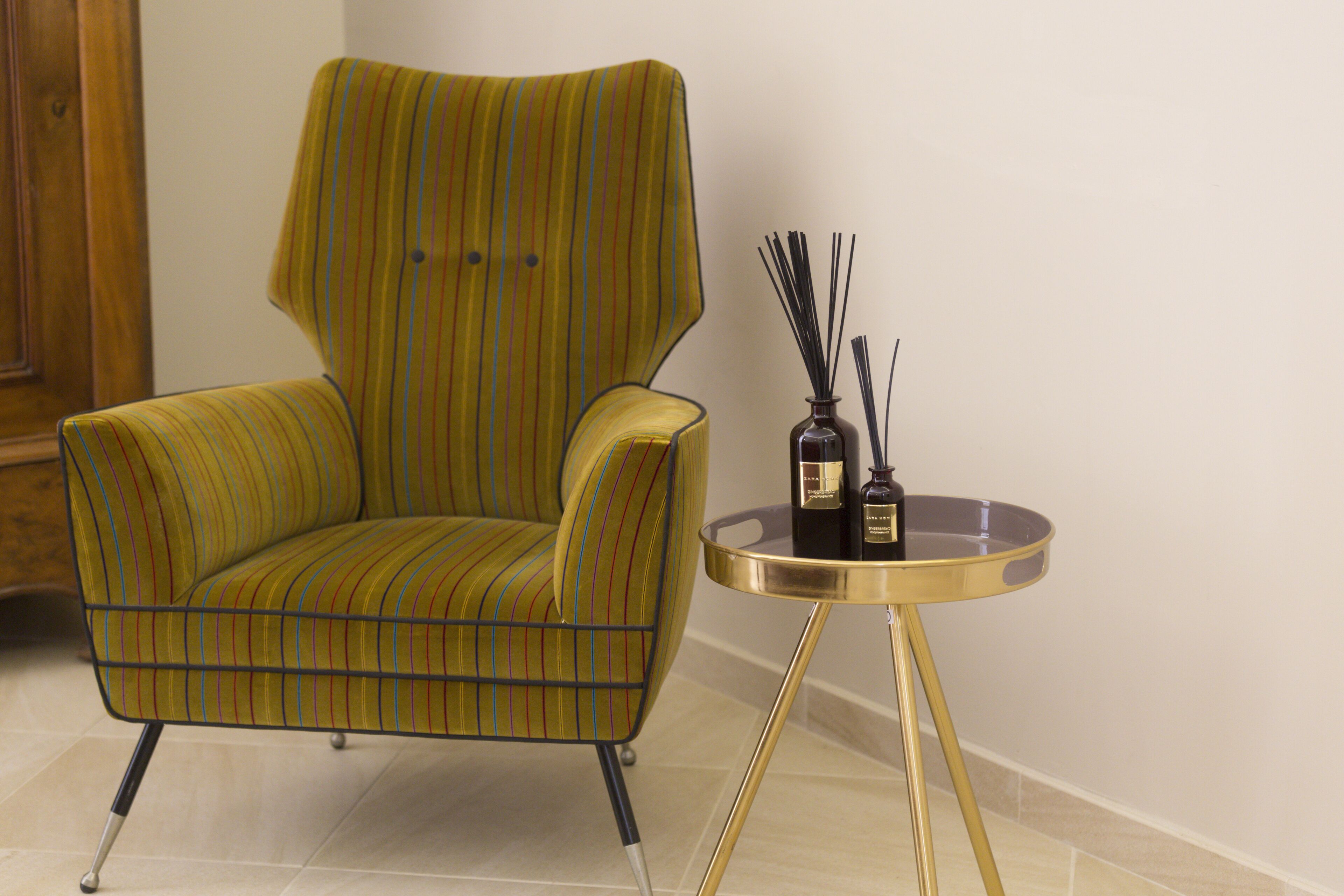 Een gestreepte fauteuil met een klein, rond tafeltje ernaast.