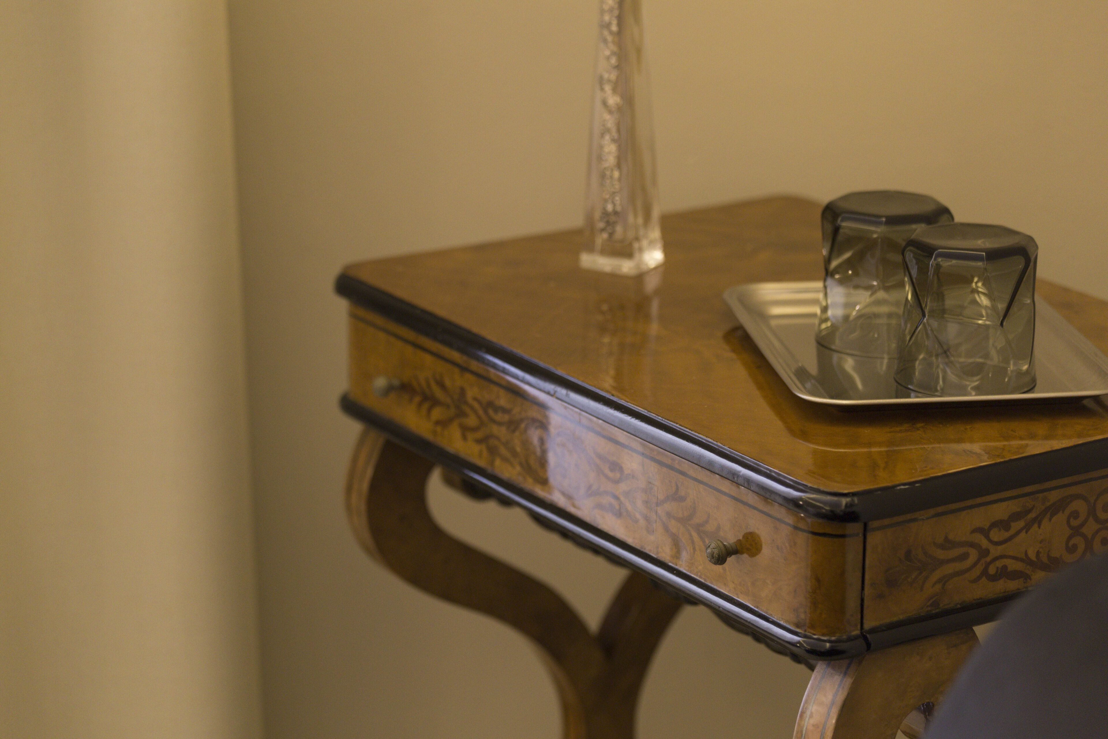 A wooden table with a tray holding two glasses and a tall glass.