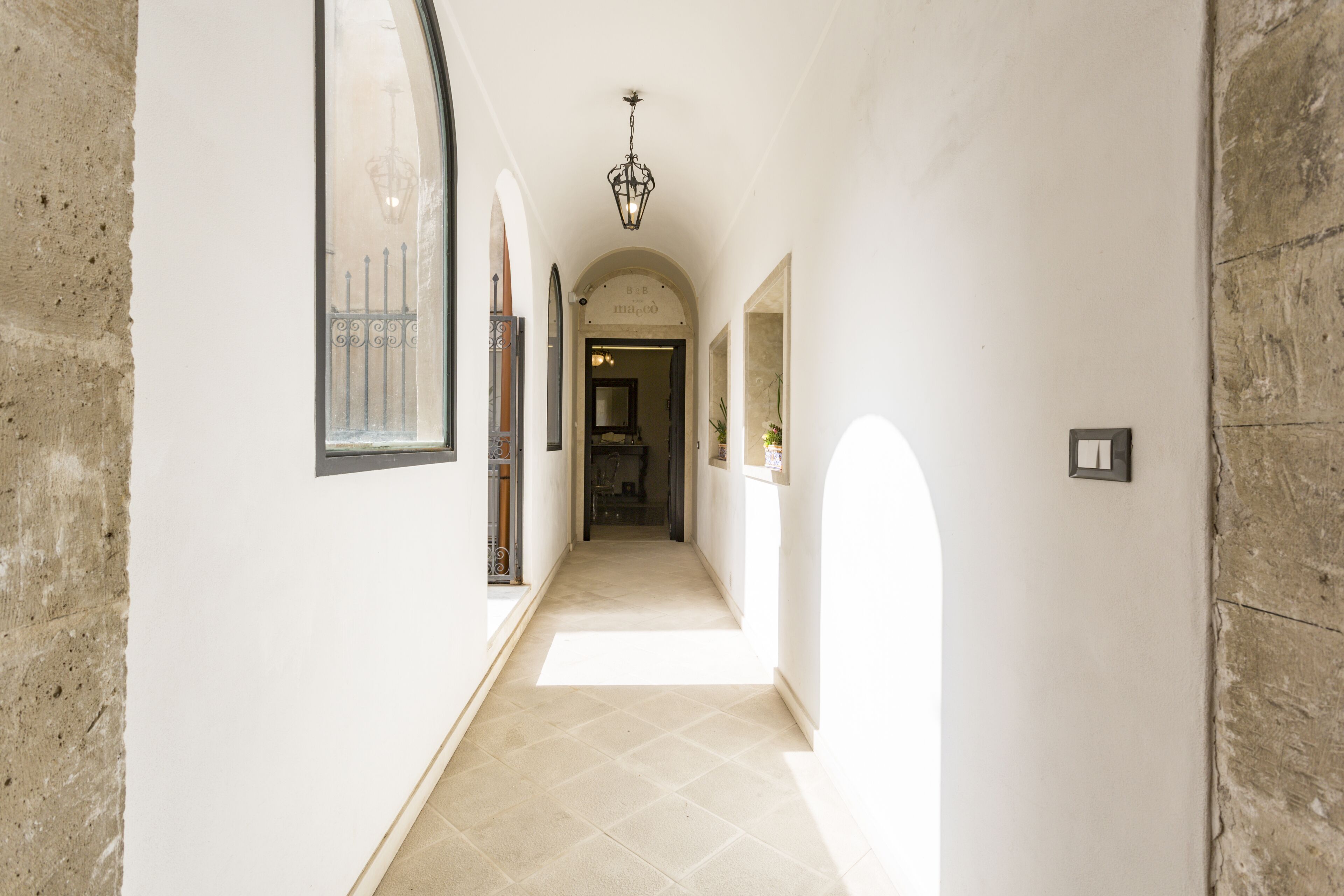 Un corridoio con porte ad arco, pavimento piastrellato e lampadario.