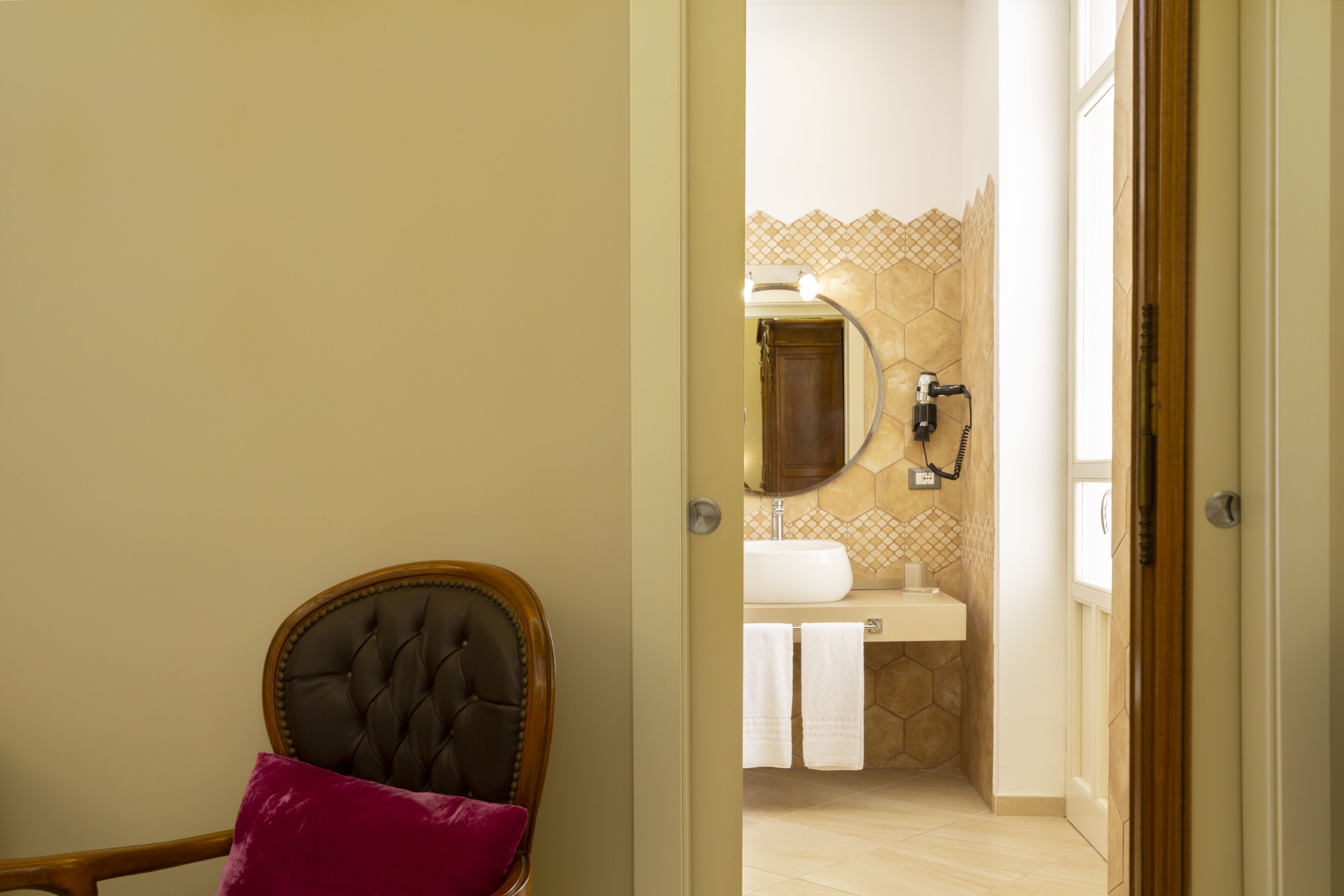 A doorway leading to a bathroom with a sink, mirror, and towel rack.
