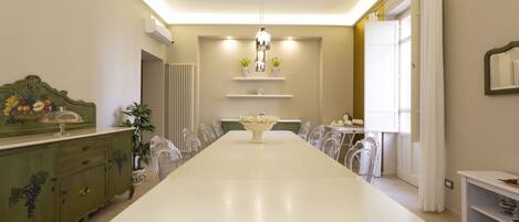 Un comedor con una mesa larga, sillas, una araña y un aparador decorativo.