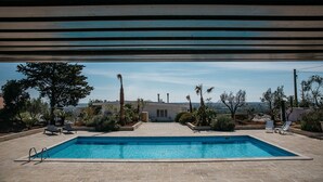 A rectangular swimming pool with a clear blue water, surrounded by a stone patio. There are lounge chairs and a palm tree in the background. - Villa de Donatis Charming Guest House (Casarano)