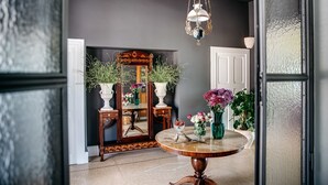 A room with a round wooden table, a mirror, and various vases with flowers. - Villa de Donatis Charming Guest House (Casarano)