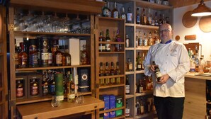 Un espace bar avec des étagères remplies de différentes bouteilles d’alcool et de verres.