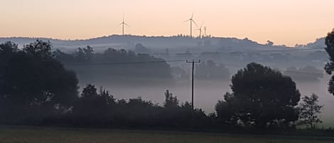 A rural landscape with wind turbines and a misty field.