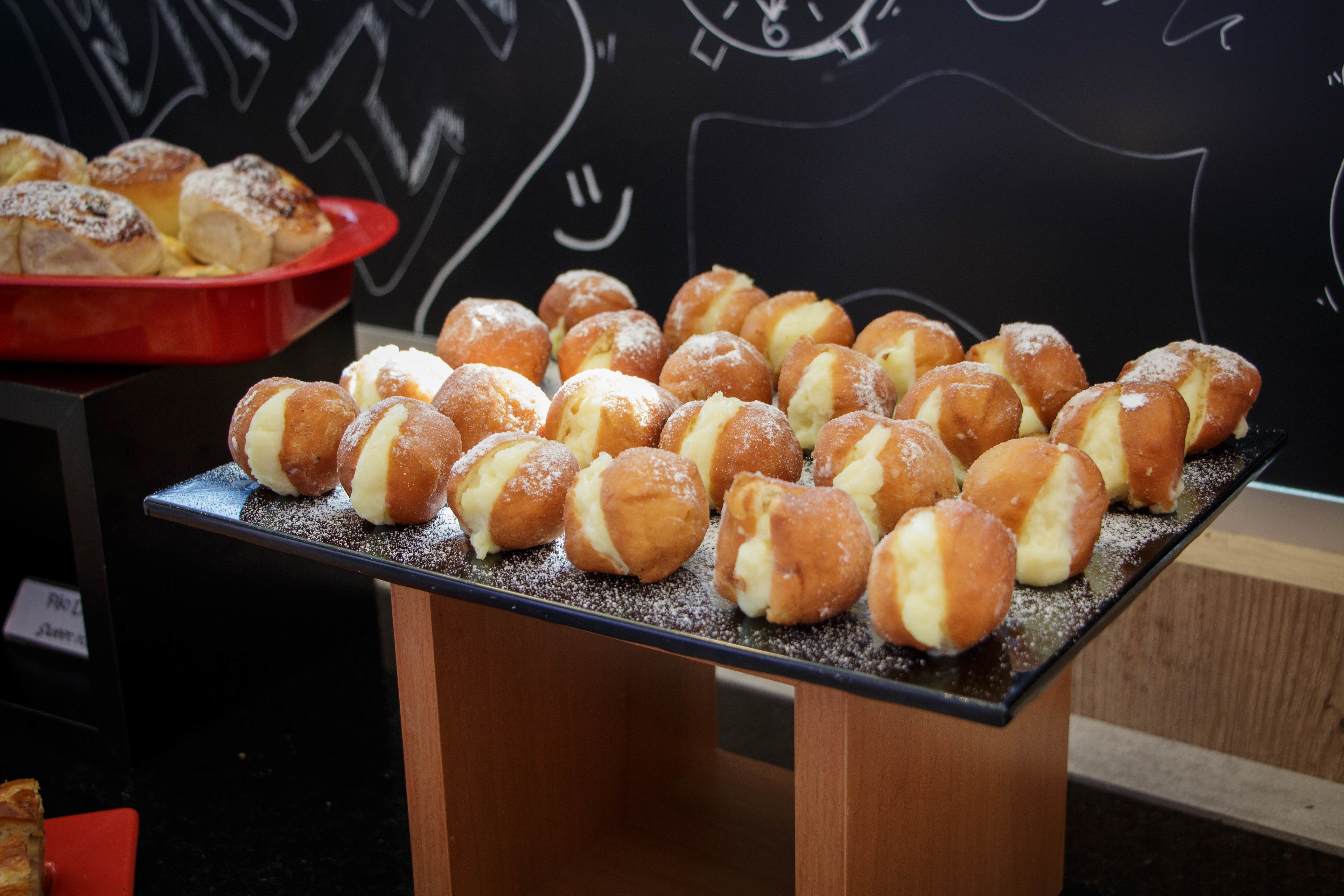 A display of cream puffs on a wooden stand with a chalkboard background.