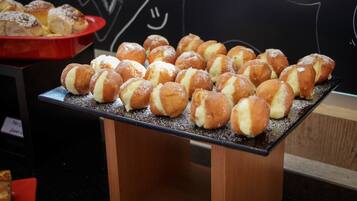 A display of cream puffs on a wooden stand with a chalkboard background.