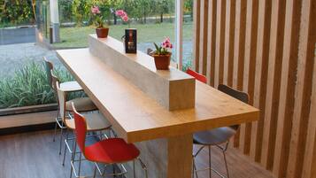 A modern kitchen with a large island, red chairs, and hanging pendant lights.