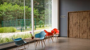 A modern room with a large window, a wooden door, and a seating area with colorful chairs and a small table. - ibis Itatiba (Itatiba)