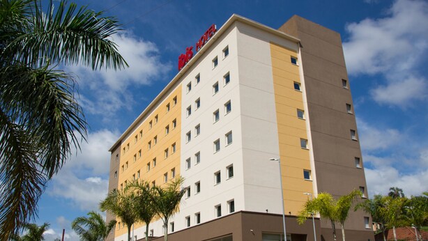 A multi-story hotel with a flat facade, multiple windows, and a prominent red sign at the top.