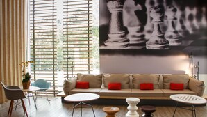 A modern living room with a beige sofa, red cushions, a round coffee table, and a chessboard mural on the wall. - ibis Itatiba (Itatiba)