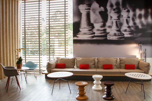 A modern living room with a beige sofa, red cushions, a round coffee table, and a chessboard mural on the wall. - ibis Itatiba (Itatiba)