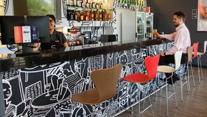 A bar area with a bartender, a variety of liquor bottles, and seating for customers. - ibis Itatiba (Itatiba)