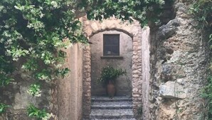 A narrow stone pathway leading to a rustic building with a window and a potted plant. - Agriturismo Colloreto (Morano Calabro)