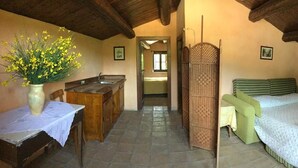 A rustic room with a bed, a desk, and a vase of yellow flowers. - Agriturismo Colloreto (Morano Calabro)