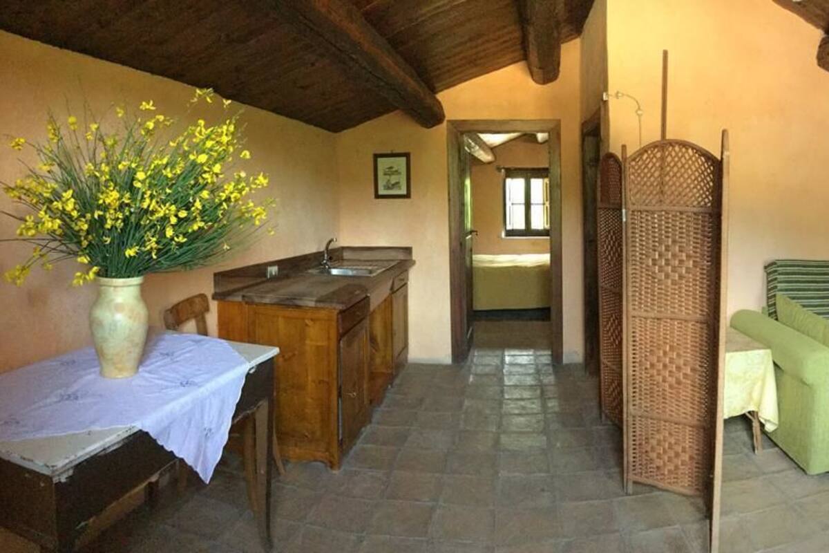 A rustic room with a bed, a desk, and a vase of yellow flowers.