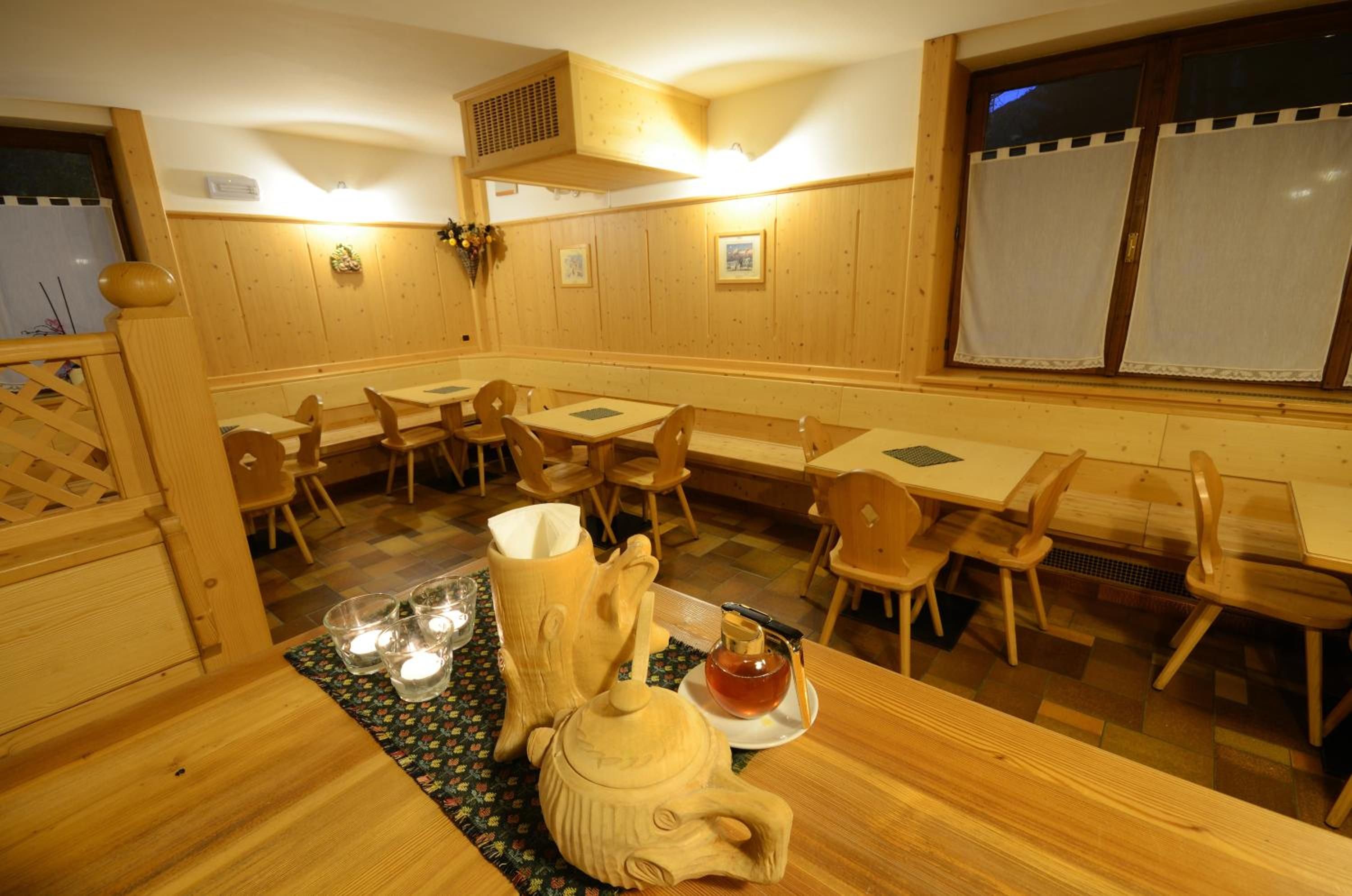 Un interior de madera con mesas y sillas, un jarrón decorativo y un hervidor sobre una mesa.