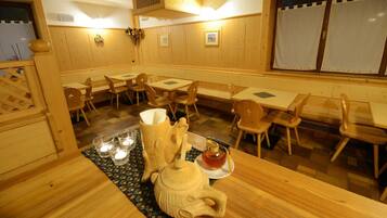 Un interior de madera con mesas y sillas, un jarrón decorativo y un hervidor sobre una mesa.