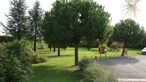 A parking area with a red fire hydrant, a directional sign, and a car. - Hotel Fiore (Fiorenzuola d'Arda)