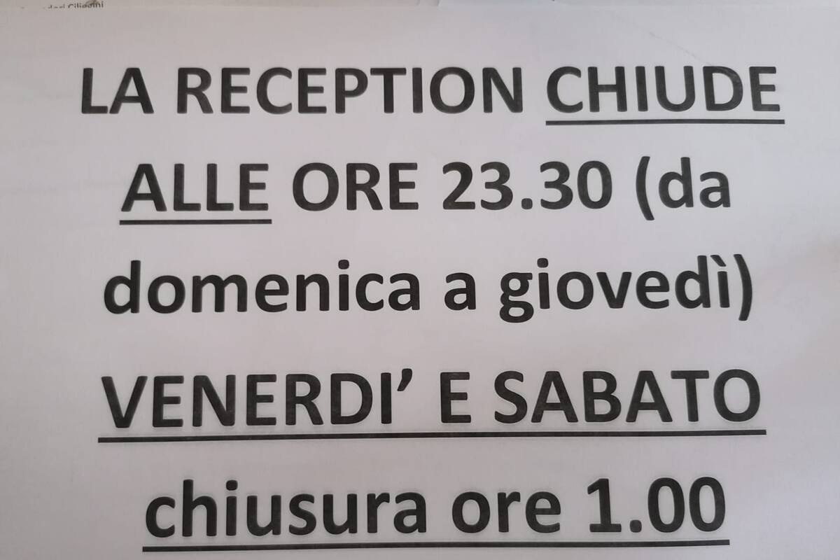 A sign with the text "LA RECEPTION CHIUDE alle ore 23.30 (da domenica a giovedì) VENERDI' E SABATO chiusura ore 1.00".