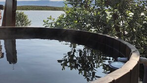 A hot tub with a clear view of a lake and mountains in the background. - Kaldbaks-kot Cottages  (Husavik)