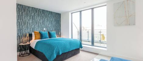 A modern bedroom with a large bed, a view of the city, and a balcony.