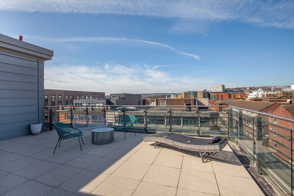 A rooftop terrace with a glass balustrade, lounge chairs, and a seating area. - KSpace @ The Point (Sheffield)