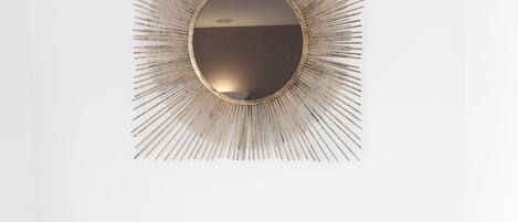 A modern vanity with a sunburst mirror, a small table with potted plants, and a hairdryer.