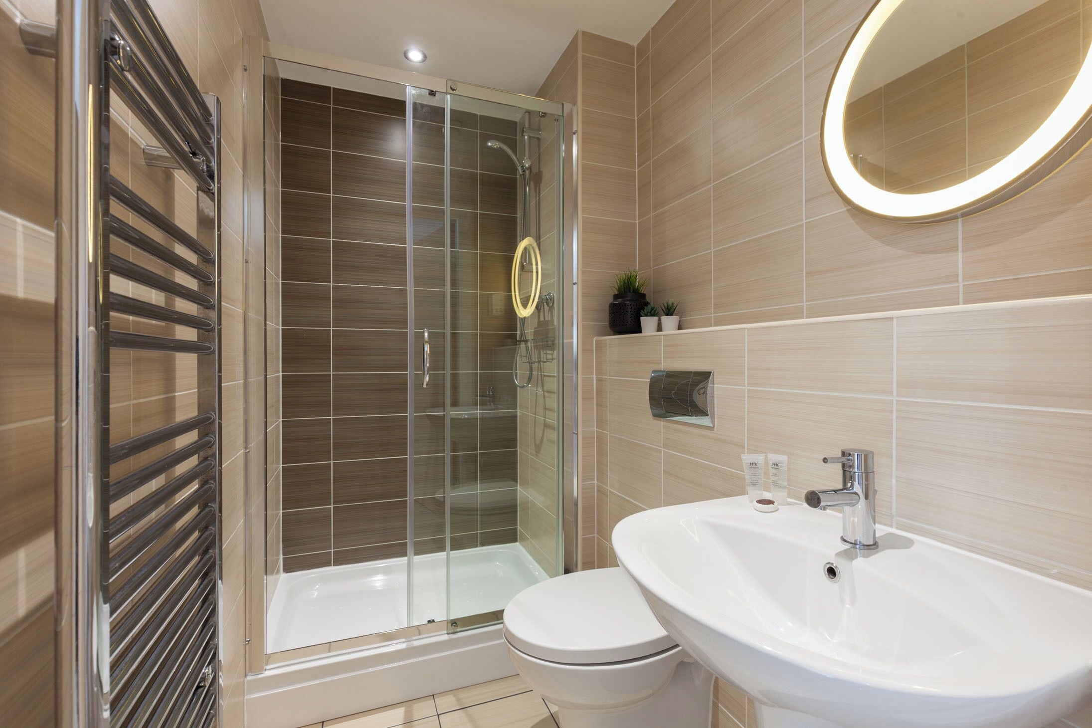 A modern bathroom with a glass-enclosed shower, a white sink, and a toilet.