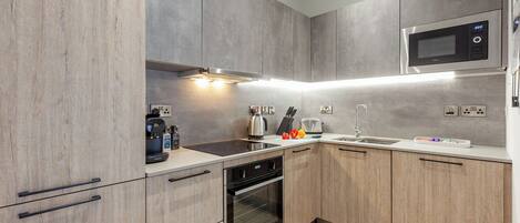 A modern kitchen with a built-in oven, microwave, and a coffee machine.